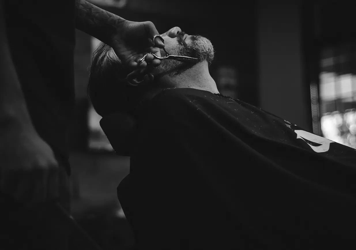 A man getting his hair cut by another person.